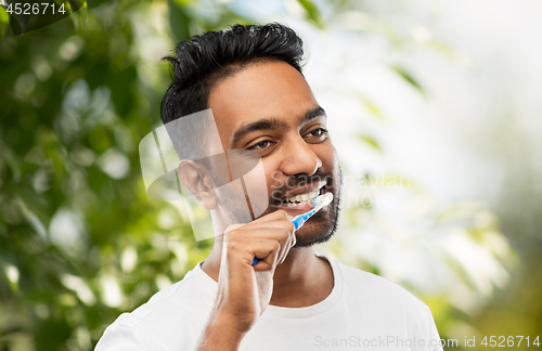 Image of indian man with toothbrush cleaning teeth