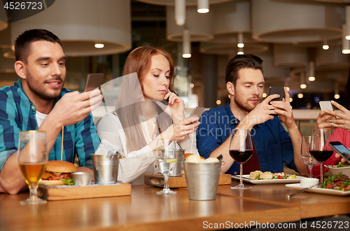 Image of friends with smartphones at restaurant