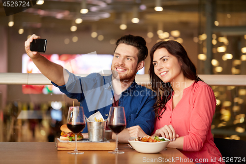 Image of couple taking selfie by smartphone at restaurant