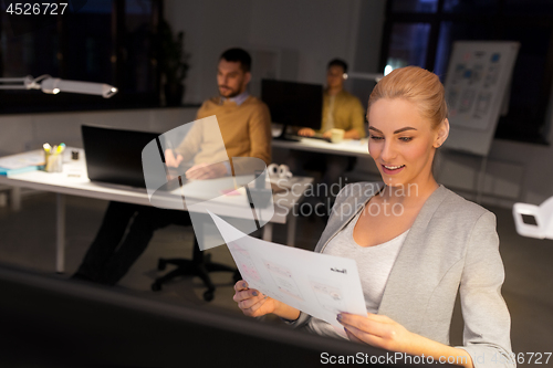 Image of designer working with papers at night office