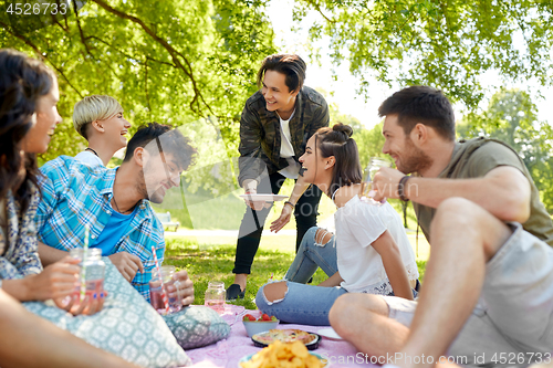 Image of friends with drinks and food at picnic in park