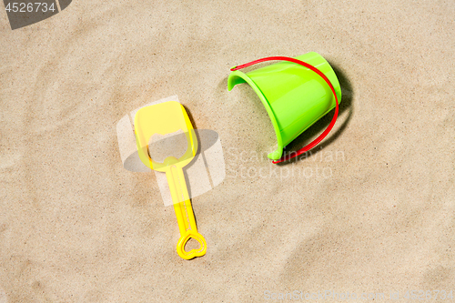 Image of toy bucket and shovel on beach sand
