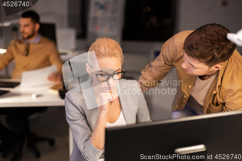 Image of business team with computer working late at office