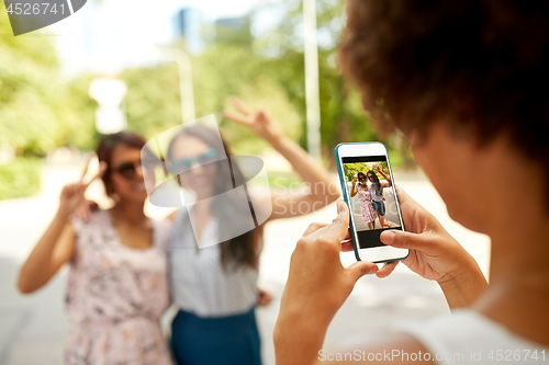 Image of woman photographing her friends in summer park