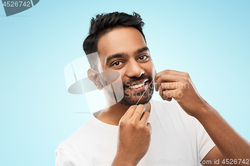 Image of indian man with dental floss cleaning teeth