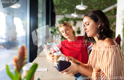 Image of female friends paying for coffee at cafe