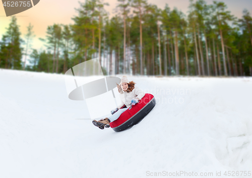 Image of happy teenage girl sliding down hill on snow tube