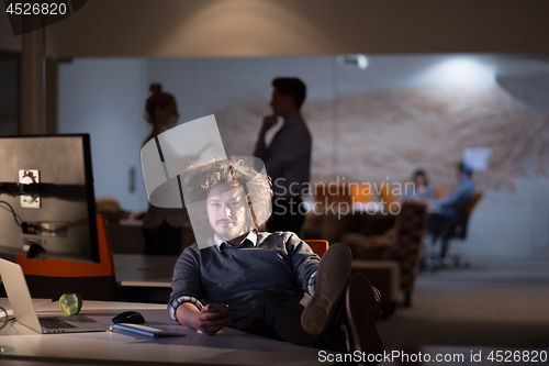 Image of businessman sitting with legs on desk at office