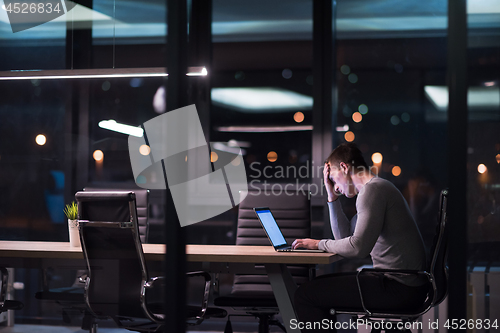 Image of man working on laptop in dark office