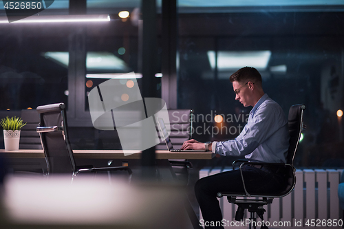 Image of man working on laptop in dark office