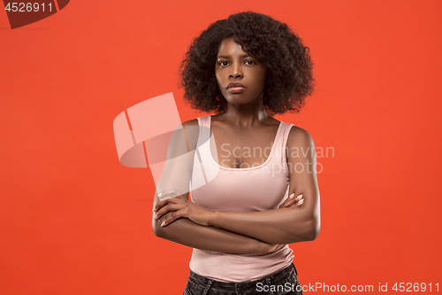 Image of The serious business woman standing and looking at camera against red background.
