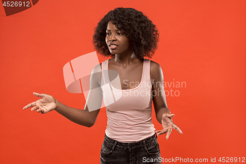 Image of Beautiful female half-length portrait isolated on red studio backgroud. The young emotional surprised woman