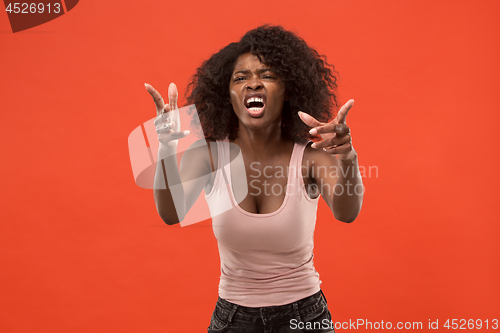 Image of The young emotional angry woman screaming on red studio background