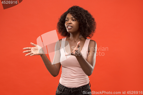 Image of Beautiful female half-length portrait isolated on red studio backgroud. The young emotional surprised woman