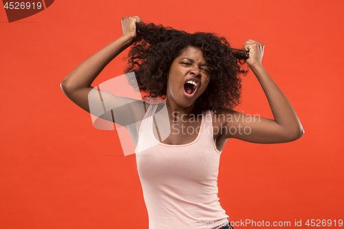 Image of The young emotional angry woman screaming on red studio background