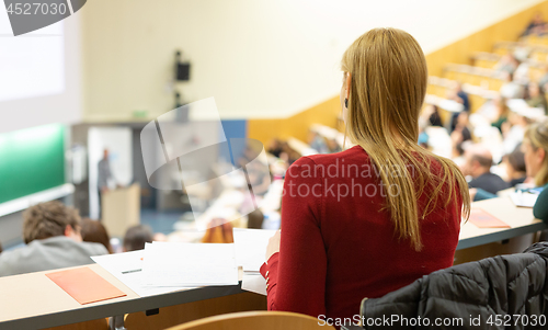 Image of Female student attending faculty lecture workshop making notes.