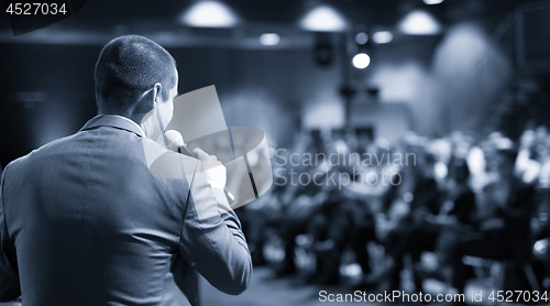 Image of Public speaker giving talk at business event.