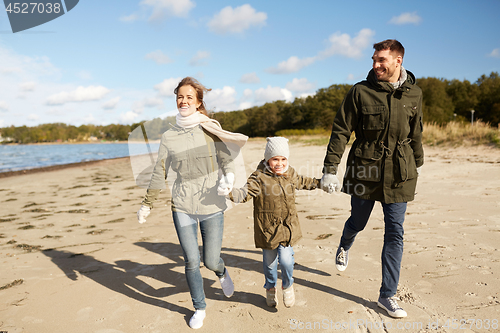 Image of happy family running along autumn beach