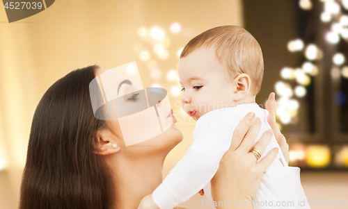 Image of mother kissing baby over christmas lights