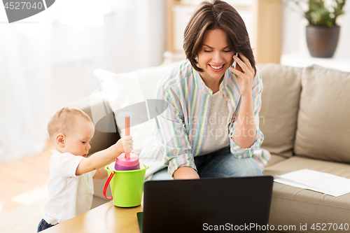 Image of working mother with baby calling on smartphone