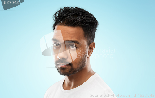 Image of sad young indian man over blue background