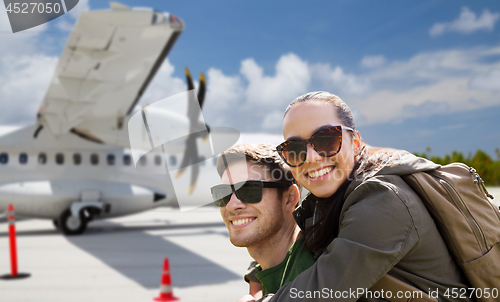 Image of couple of tourists with backpacks over plane