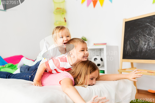 Image of happy little kids having fun in bed at home