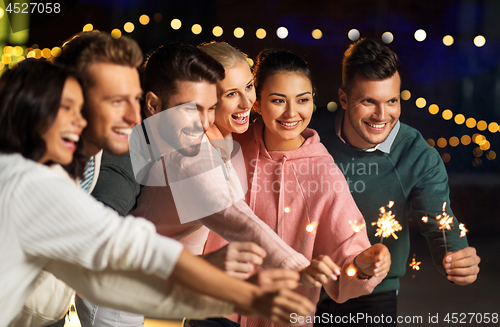 Image of happy friends with sparklers at rooftop party