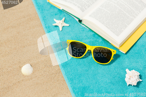 Image of sunglasses and book on beach towel on sand