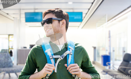 Image of smiling man with backpack over airport terminal