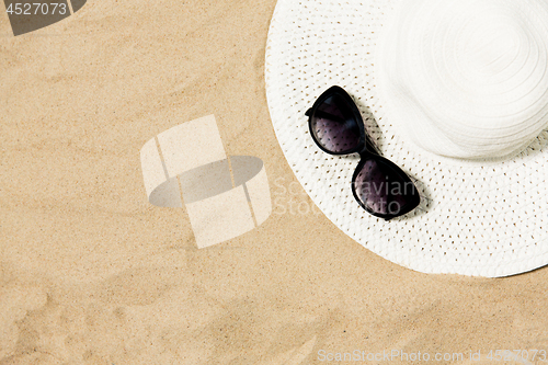 Image of straw hat and sunglasses on beach sand