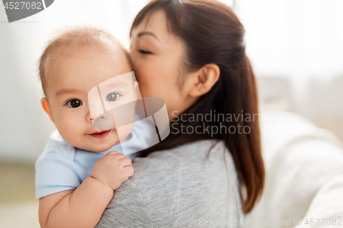 Image of close up of happy mother kissing baby son at home