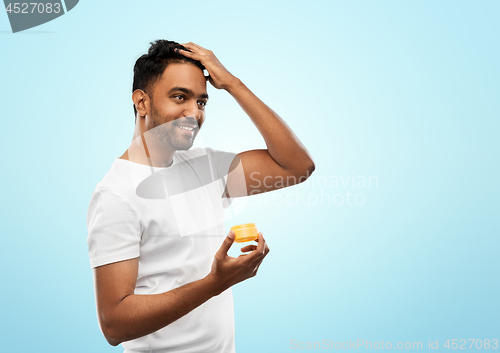 Image of indian man applying hair wax or styling gel