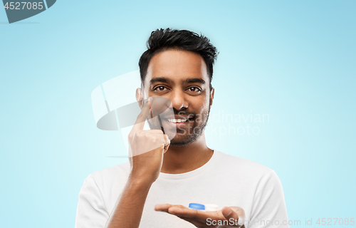 Image of young indian man applying contact lenses