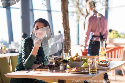 Image of young woman  having lunch at restaurant