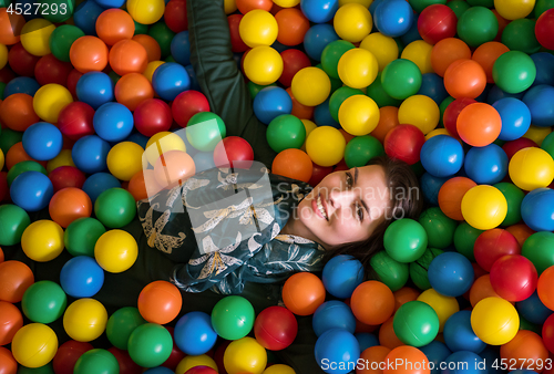 Image of young mom playing with kids in pool with colorful balls