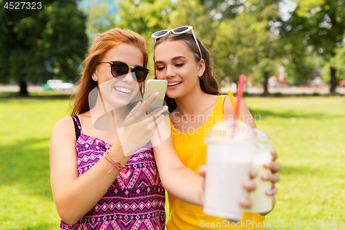 Image of teenage girls with smartphone and shakes in park