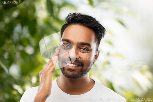 Image of smiling indian man touching his face