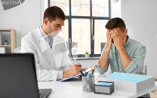 Image of doctor with clipboard and male patient at hospital