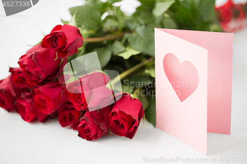 Image of close up of red roses and greeting card with heart