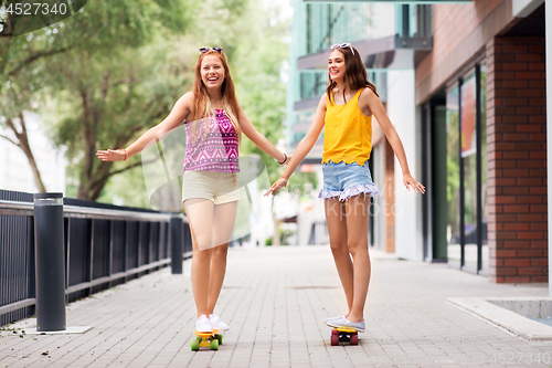 Image of teenage girls riding skateboards in city