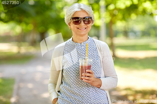 Image of senior woman drinking takeaway shake at park