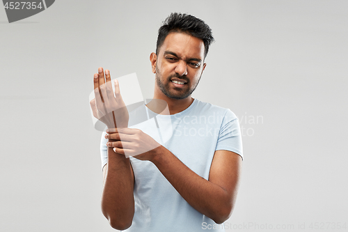 Image of unhappy man suffering from pain in hand