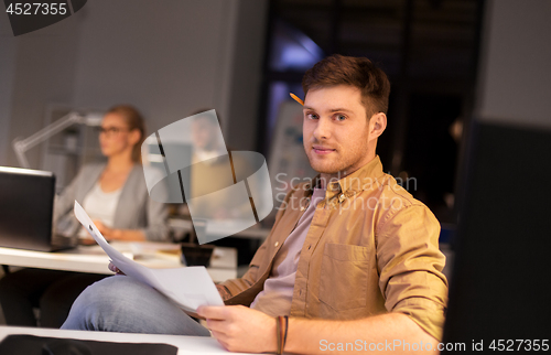 Image of man with papers working at night office