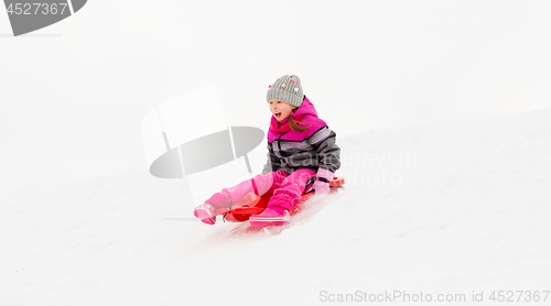 Image of happy little girl sliding down on sled in winter