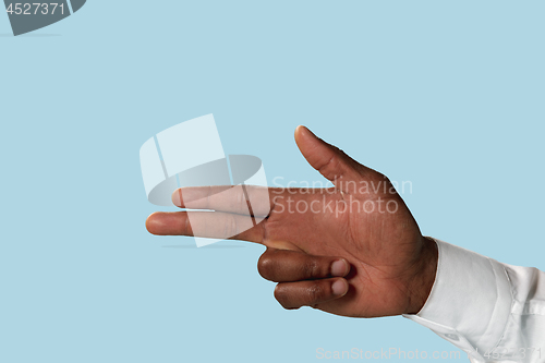 Image of Male hand demonstrating a gesture of gun isolated on blue background