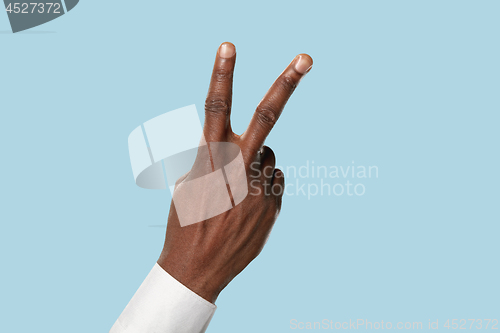 Image of Male hand demonstrating a gesture of peace isolated on blue background