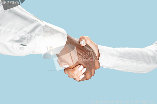 Image of Two male hands shaking isolated on blue studio background