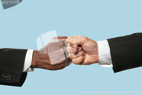 Image of Two male hands competion in arm wrestling isolated on blue studio background