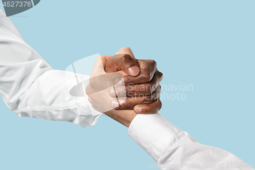 Image of Two male hands competion in arm wrestling isolated on blue studio background